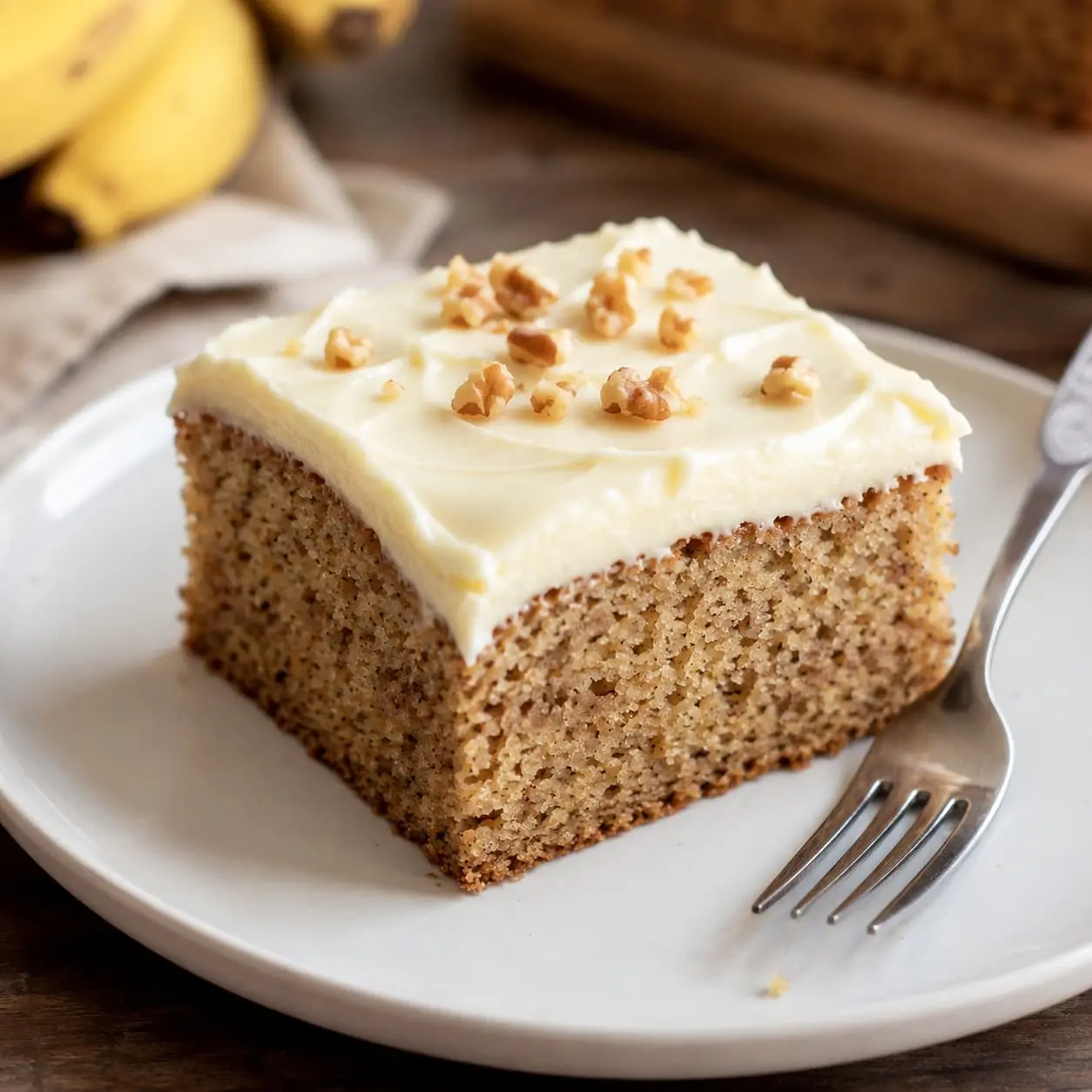 banana cake recipe slice with cream cheese frosting & chopped walnuts